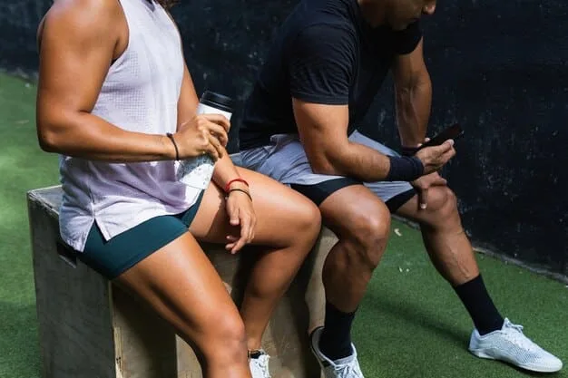 A close-up shot of a Premier League team's physio working on a player's injured leg on the sidelines during a match. The focus is on the physio's hands and the player's pained expression. Medical equipment is visible in the background.