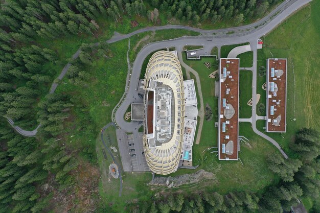 An aerial view of a newly constructed MLS stadium surrounded by parks, residential buildings, and commercial spaces. The stadium's design incorporates sustainable elements, such as solar panels and green roofs, blending into the urban environment.