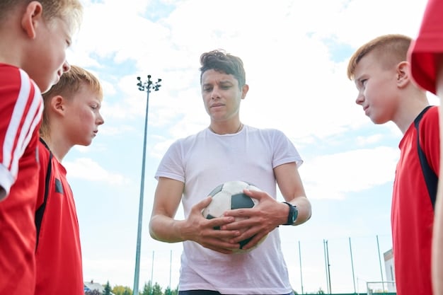 A group of young football players, aged between 10-12, participating in a training session at a Premier League academy. The players are wearing the academy's training kit and are being closely observed by a group of scouts and coaches from the sideline. The focus is on their agility, passing accuracy, and teamwork.
