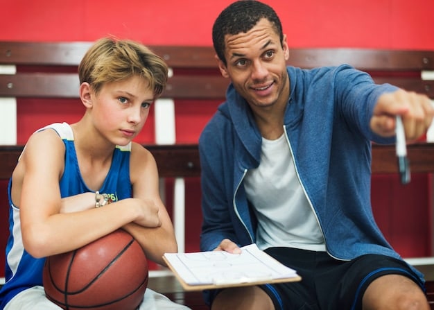 A close-up shot of a Premier League academy coach giving instructions to a young player during a training session. The coach is animated and passionate, using hand gestures to explain a tactical concept. The player is attentive and focused, listening intently to the coach's advice.
